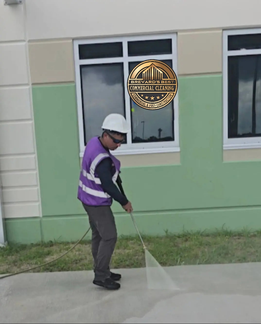 Worker pressure washing commercial building exterior